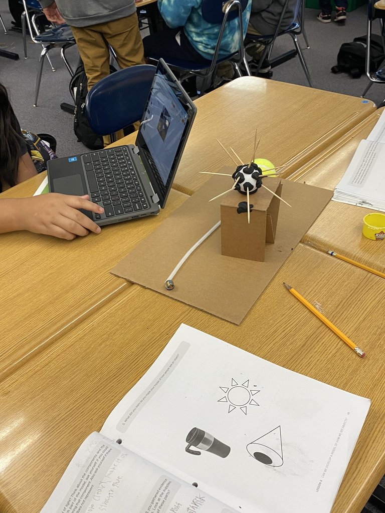 student with chromebook and science model